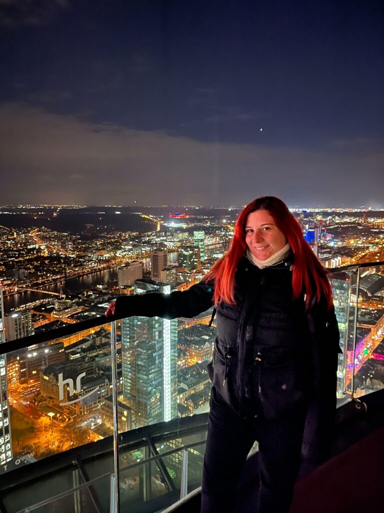 Persona con el pelo rojo en el mirador del Main Tower de Frankfurt, con la ciudad iluminada de noche