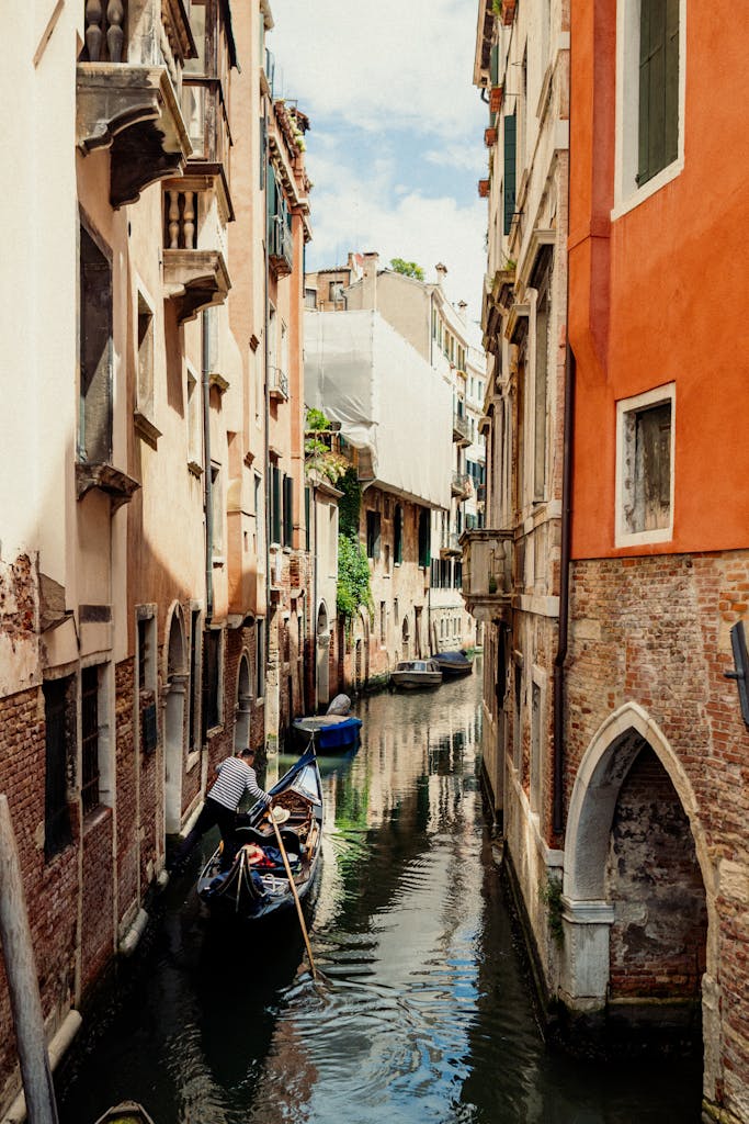 Venetian canal scenic view with a gondola, historic tenements, and reflections.