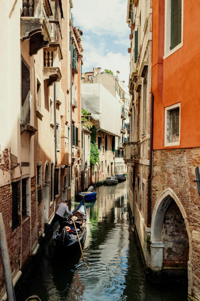 Venetian canal scenic view with a gondola, historic tenements, and reflections.